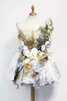 a dress made out of fabric and flowers on a mannequin headdress