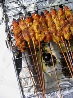 several skewers of food sitting on top of aluminum foil covered in sauces