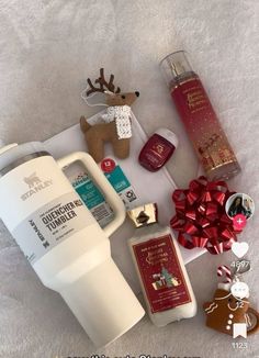 the contents of a christmas gift laid out on a white blanket with red bows and reindeer decorations