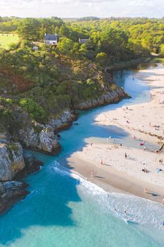 an aerial view of people on the beach and in the water near some cliffs with houses