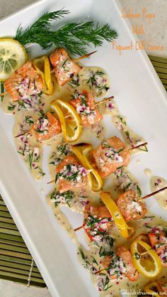 a white plate topped with shrimp and lemons on skewers next to a lemon wedge