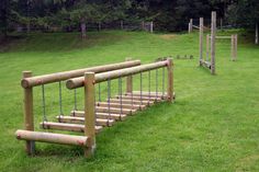 a set of wooden stairs made out of logs and chains in a grassy area with trees behind them