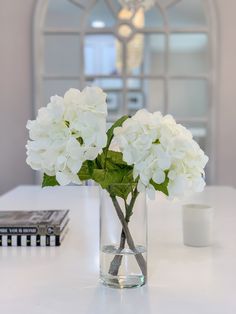 white flowers are in a clear vase on a table