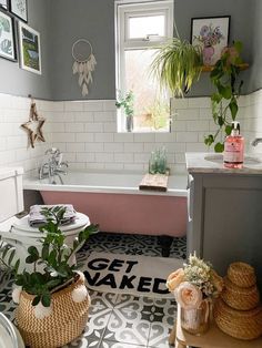 a bathroom with a tub, toilet and plants in baskets next to the bathtub