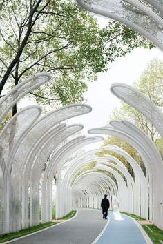 a man and woman walking down a street lined with white arches