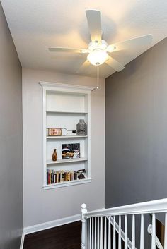 an empty room with a ceiling fan and bookshelf