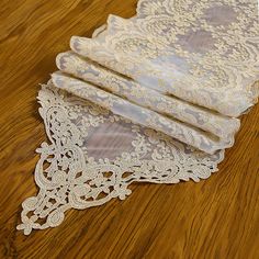 three pieces of white lace sitting on top of a wooden floor next to each other