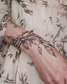 a woman's arm with leaves on it and a clock in the corner behind her