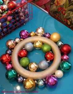 a wreath made out of christmas ornaments on a blue table next to a red basket