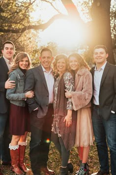 a group of people standing next to each other in front of trees and sun beams