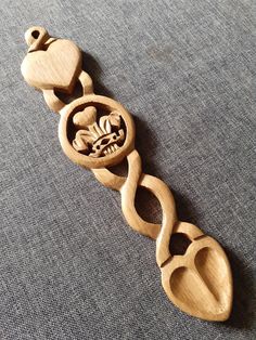 a wooden bracelet with two hearts and an owl on it's side, sitting on a gray surface