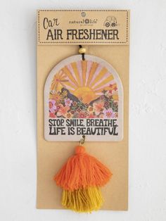 an air freshener hanging on a wall with a tasseled keychain