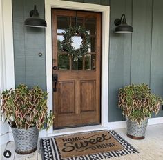 two potted plants sit on the front porch next to a welcome mat that says home sweet