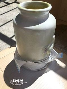 a large white vase sitting on top of a cardboard box