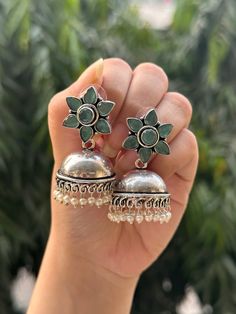 These high quality German silver earrings are the perfect addition to any ethnic or western look. The stone used reflects light and gives a look of mystery and allure to your outfit. These earrings will last you forever and are sure to be your go to pair! Plus they came in an adorable flower shape!  Available in 4 stunning colours, these earrings need to be in your collection!  They are limited edition and unique styles so only 1 of each is available and will not be restocked in the future, so grab yours today!  In case of any query, please feel free to reach out to us. Happy shopping! Bohemian Silver Bridal Earrings With Latkans, Bohemian Bridal Earrings With Latkans In Silver, Bohemian Bridal Silver Earrings With Latkans, Bohemian Silver Bridal Earrings With Meenakari, Traditional Silver Drop Flower Earrings, Traditional Silver Flower Earrings For Festive Occasions, Traditional Silver Flower Earrings, Elegant Silver Jhumkas For Festival, Bohemian Sterling Silver Jhumkas For Festivals