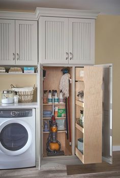 an open cabinet in the middle of a kitchen with a washing machine and dryer