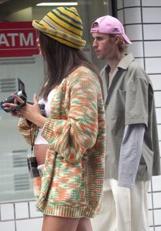 a man and woman standing next to each other in front of a storefront window