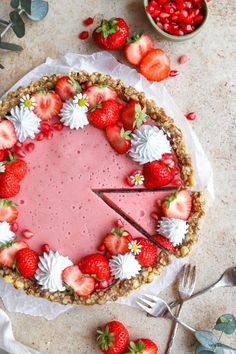 a pie with strawberries and whipped cream is on the table next to some berries