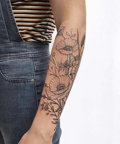 a woman's arm with flowers on it and a striped shirt in the background