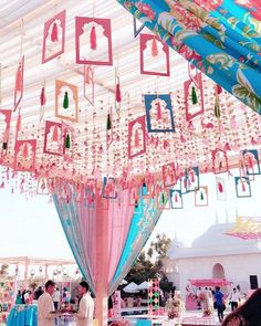 people are standing under a canopy decorated with pink and blue decorations, hanging from it's ceiling