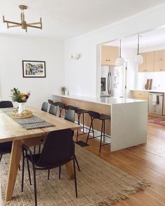 a dining room table with chairs and an island in the middle is surrounded by wood flooring