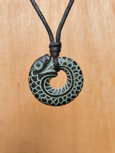 a black necklace with a circular pendant hanging from it's side on a wooden surface