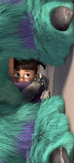 a young boy in a furry green costume looking out from behind a large stuffed animal