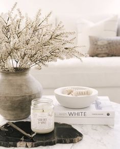 a table topped with a vase filled with flowers next to a book and candle holder