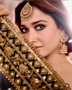 a beautiful woman in a bridal outfit holding up her gold necklace and matching jewelry