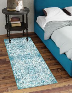 a blue bed sitting next to a night stand on top of a wooden floor