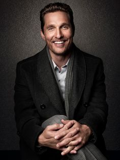 a man in a suit and tie sitting down with his hands folded over his chest