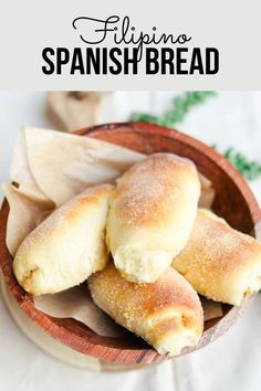 bread rolls in a wooden bowl on a white tablecloth with text overlay that reads, filipino spanish bread