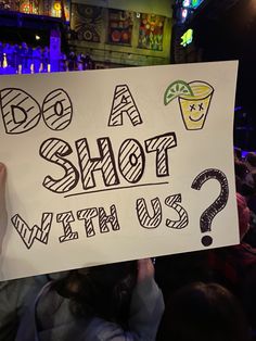 a person holding up a sign that says do a shot with us?