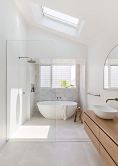 a large white bathroom with a skylight above the bathtub and sink, along with a wooden countertop