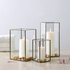 three candles in glass containers with rocks on the floor