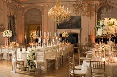 an elegant wedding setup with white flowers, candles and chandeliers in the ballroom