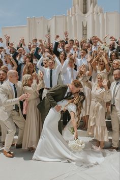 a bride and groom kissing in front of a large group of people at their wedding