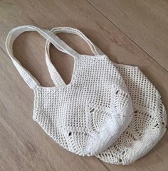 two white purses sitting on top of a wooden floor next to an empty bag