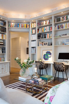 a living room filled with lots of white furniture and bookshelves full of books