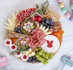 an assortment of cheeses, crackers and fruits on a platter with candy