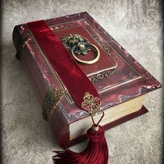 an open book with a red tassel on the cover and a gold ring hanging from it