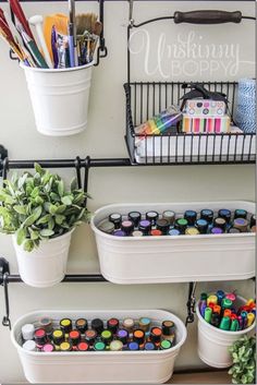 three white buckets filled with paint sitting on top of a shelf next to a potted plant