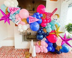 a bunch of balloons and streamers in the shape of a happy birthday sign on a brick floor