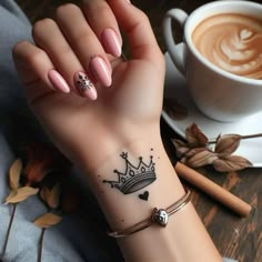 a woman's hand with a tattoo on it and a cup of coffee in the background