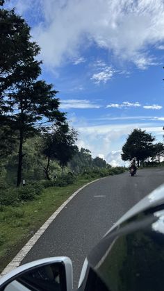 a car driving down the road with trees on both sides and blue skies above it