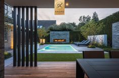 an outdoor dining area with a pool and fire place in the center, surrounded by wooden flooring