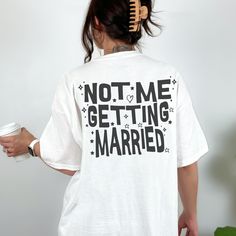 a woman wearing a white t - shirt with the words not me getting married printed on it