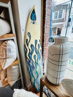 a surfboard sitting on top of a wooden shelf next to a vase and other items