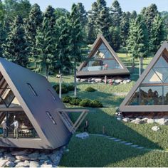 three triangular shaped houses in the middle of a grassy area with trees and rocks around them