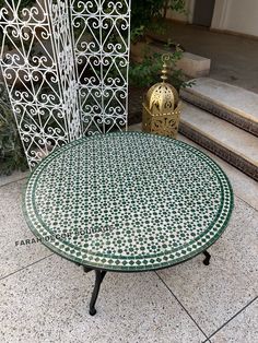 a green and white table sitting on top of a sidewalk next to some steps,